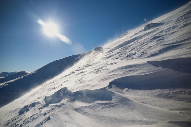 Textura de nieve Viento fuerte en las montañas de los Cárpatos en invierno en un día soleado Patrones esculpidos por el viento en la superficie de la nieve