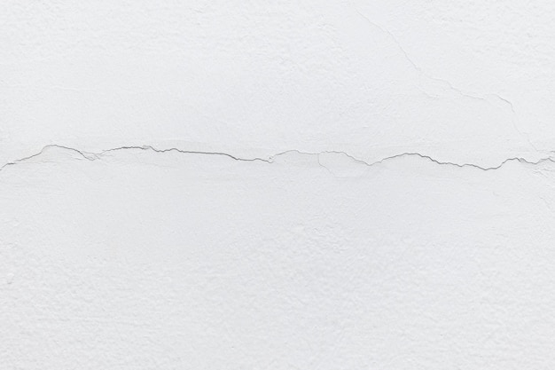 La textura de la pared de hormigón blanco tiene grietas