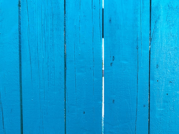 La textura de una pared de madera resistida cerca hecha de tablas viejas azules