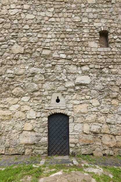 La textura de la pared de piedra medieval y la antigua puerta de metal