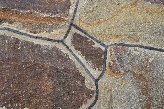 La textura de la pared de piedras de granito de diferentes formas y colores.