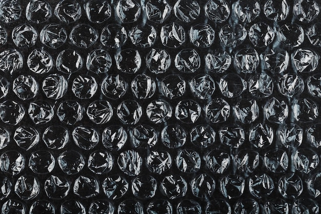 La textura de la película de burbujas de aire de embalaje sobre un fondo negro en pantalla completa