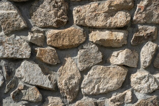 Textura de piedras antiguas de diversas formas con costuras Cerca de mampostería en mal estado Muro de piedra desigual de diferentes adoquines friables antiguos