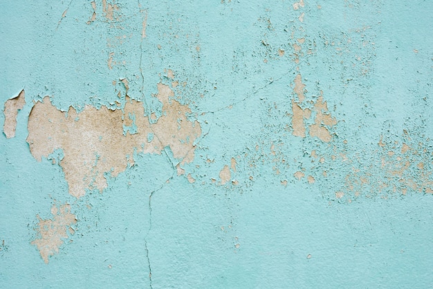 La textura de pintura vieja azul está desconchada y agrietada en la pared.