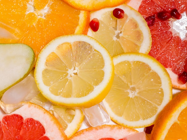 Textura de rodajas de frutas como limón y naranja, granada y pomelo con hielo. concepto de verano