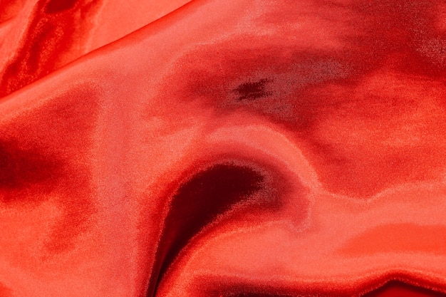 Textura roja brillante de satén de seda con pliegues.