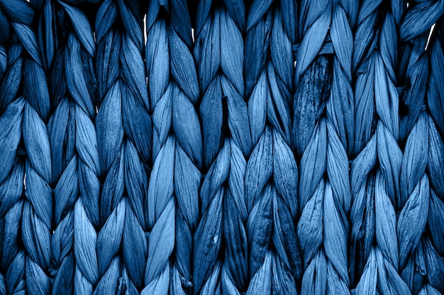 Textura rústica de mimbre natural tonificada en color monocromático azul clásico. Fotografía macro de patrón trenzado.