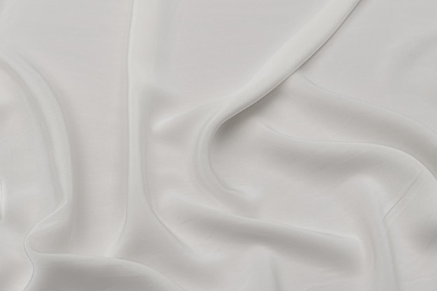 Textura de satén gris blanco que es blanco tela de plata seda panorama de fondo con un hermoso patrón de desenfoque suave natural