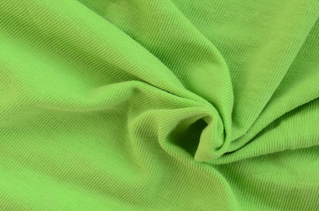 La textura de la tela es verde brillante. Material para confeccionar camisas y blusas.