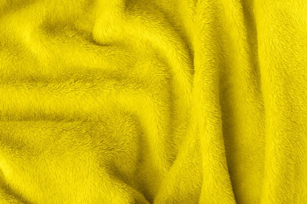 Textura de tela esponjosa iluminadora amarilla. Fondo de manta de piel sintética textil arrugado. Tendencia de color del año