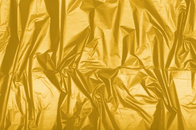 Textura de textil brillante arrugado entonado en Fortuna Gold