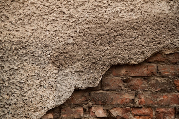 Textura de una vieja pared irregular Fondo de ladrillos viejos y grietas en yeso Tonos amarillos y marrones