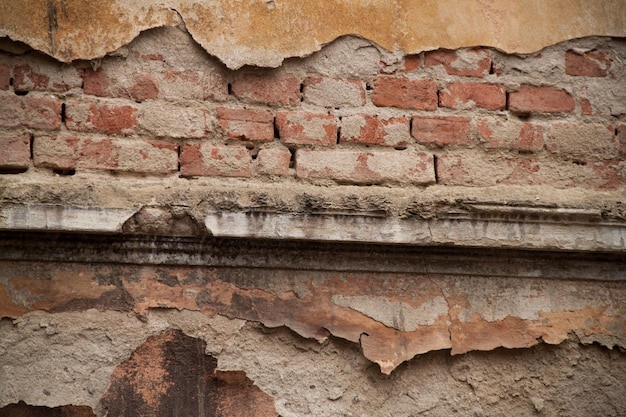 Textura de una vieja pared irregular Fondo de ladrillos viejos y grietas en yeso Tonos amarillos y marrones