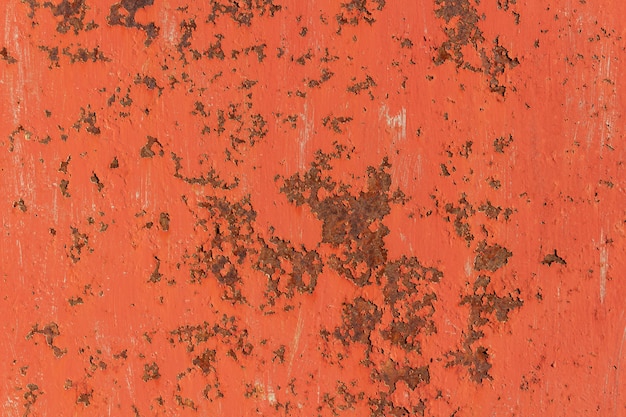 Textura de la vieja placa de metal oxidada con la pintura agrietada roja con los rasguños.