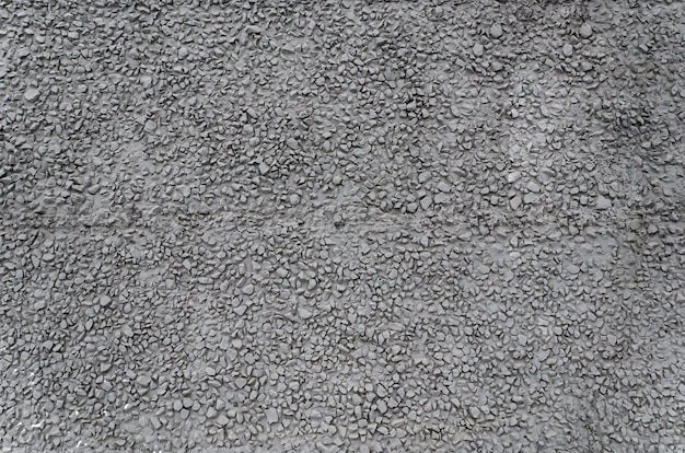 Textura de yeso de cemento de fachada de edificio gris oscuro con grava fina