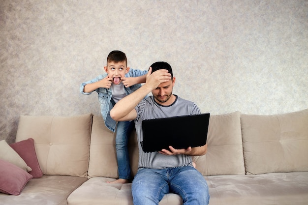 Tfather mit Laptop, der arbeitet, während Kind spielt