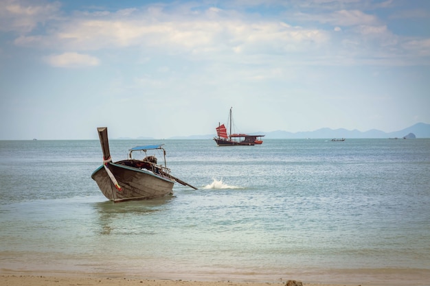 Thai Longtail-Boot am Strand von Phra Nang Going to the sea schwarzes Segelschiff mit roten Segeln