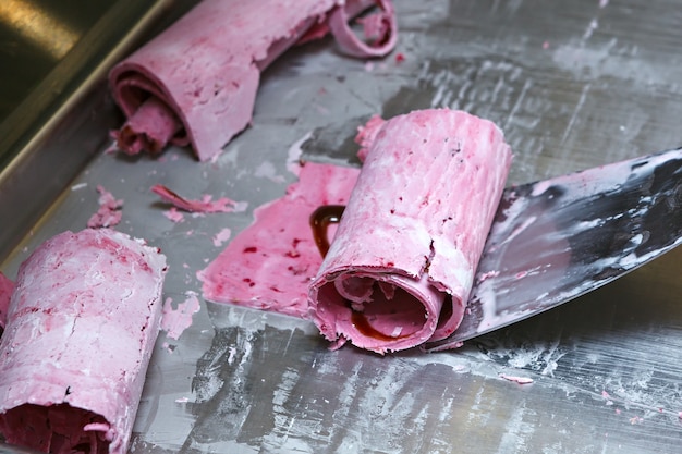 Thai Roll-Eis wird von Hand auf dem Gefrierschrank hergestellt. Süßes Dessert aus natürlichen Beeren und Zutaten. Der Prozess der Lebensmittelherstellung.