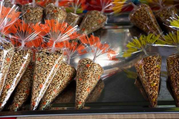 Thailänder kochen lokale Speisen geröstete Sonnenblumen Samen Getreide mit Honig und Salz in Stahlpfanne auf Gasofen für Kunden Reisende wählen leckere kaufen und essen im Straßenmarkt Bazar in Lopburi Thailand