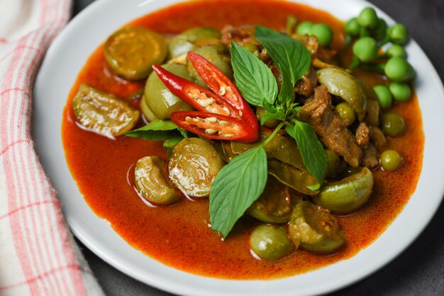 Thailändische Curry-Suppe auf weißem Teller - asiatisches Essen der roten Curry-Schweinefleischküche auf der Tischwand