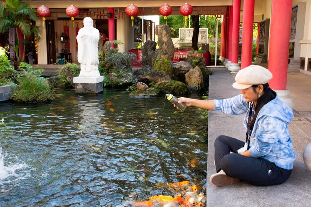 Thailändische Frau besucht und füttert am 19. Dezember 2017 in Udon Thani Thailand ausgefallene Karpfen im Teich des chinesischen Gartens im thailändisch-chinesischen Kulturzentrum mit Nahrung