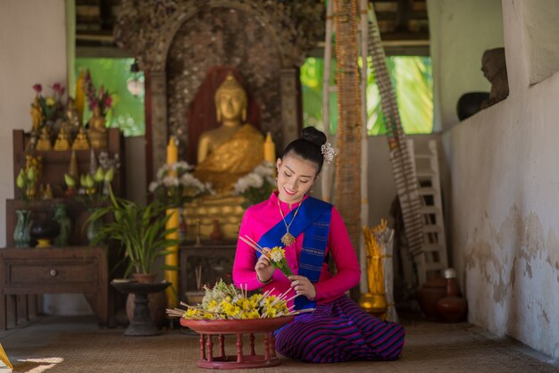 Thailändische Frau in traditioneller Tracht, die Weihrauchopfer macht