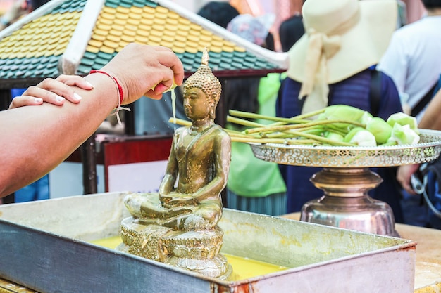 Thailändische Frauen beten buddhistische Zeremonie Buddha-Statue Zitrussaft darauf gepresst Angebot