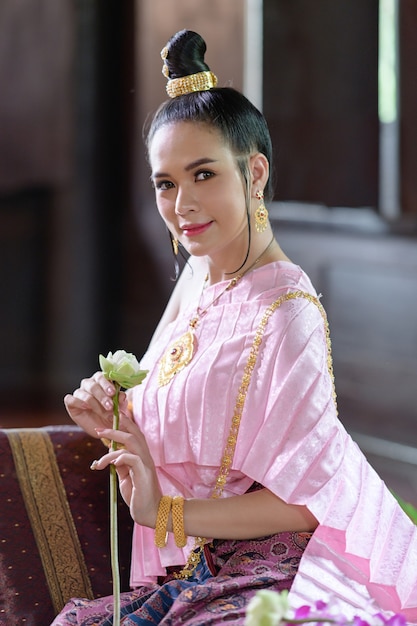 Thailändische Frauen in traditioneller thailändischer Kleidung schmücken Blumen.
