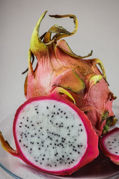 Thailändische Fruchtdrachefrucht mit Beschneidungspfad, auf einer Glasplatte, weißer Hintergrund.