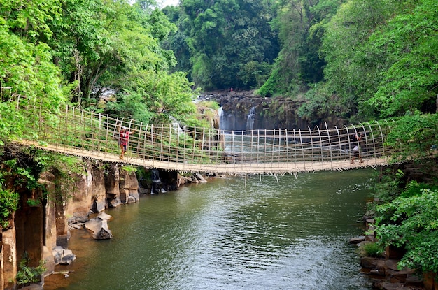 Thailändische Männer und Frauen reisen und posieren für Fotoaufnahmen auf einer Hängebrücke aus Holz und Bambus, um den Fluss an den Tad Pha Suam Wasserfällen in Pakse Champasak Laos zu überqueren