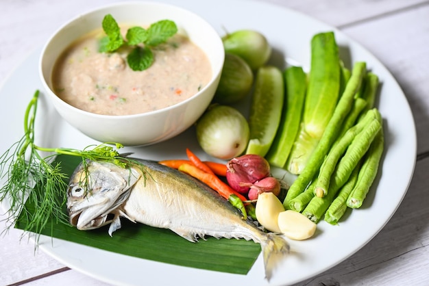 Thailändische Makrele, die Makrelenfisch kocht, gekocht mit Chili-Schalotten-Knoblauch-Grün-Auberginen-Gurke frisches Gemüse auf weißem Teller Fischmehl