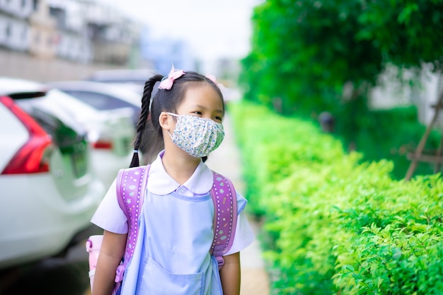 Thailändische Studentin, die eine Maske gegen Coronavirus trägt, bevor sie zur Schule geht