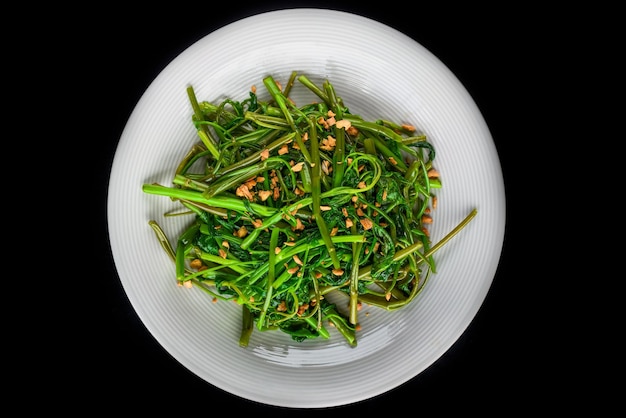 thailändischer gebratener spinat auf einer weißen platte draufsicht