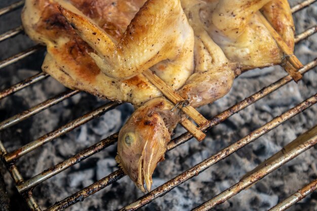 Thailändisches ganzes Huhn grillte mit Holzkohle auf Straße.