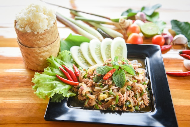 Thailändisches Lebensmittel des würzigen gehackten Schweinefleischsalats mit klebrigem Reis der Kräuter- und Gewürzbestandteile Tradition-Nordostlebensmittel Isaan.