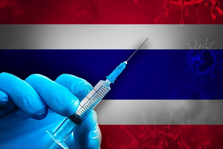 Thailand Covid19 Impfkampagne Hand in einem blauen Gummihandschuh hält Spritze vor Flagge