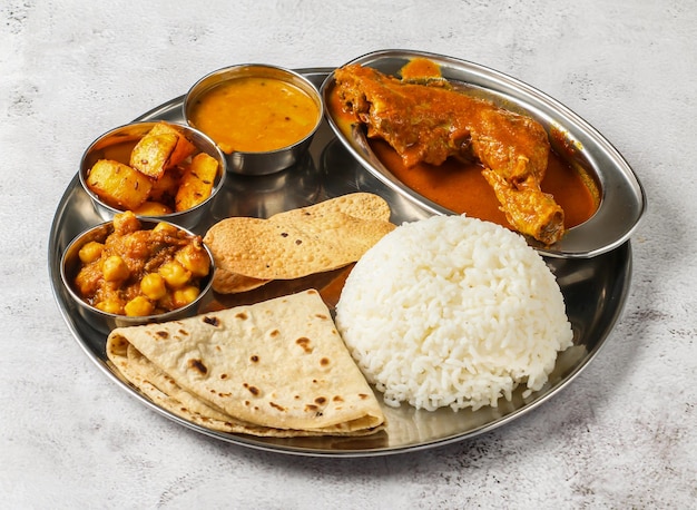 Foto thali de pollo con pollo korma chanay arroz simple aloo shorba y chapati servido en un plato aislado en el fondo vista superior de la comida picante india