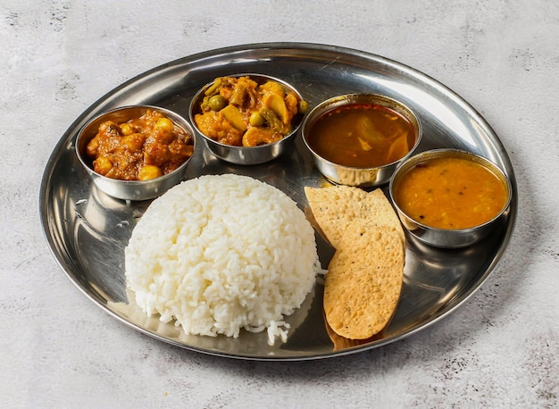 Thali de verduras con arroz simple palak dal vegetales mixtos de aloo gobi matar dal palak nachos y shorba servidos en un plato aislado en la vista superior del fondo de la comida picante india