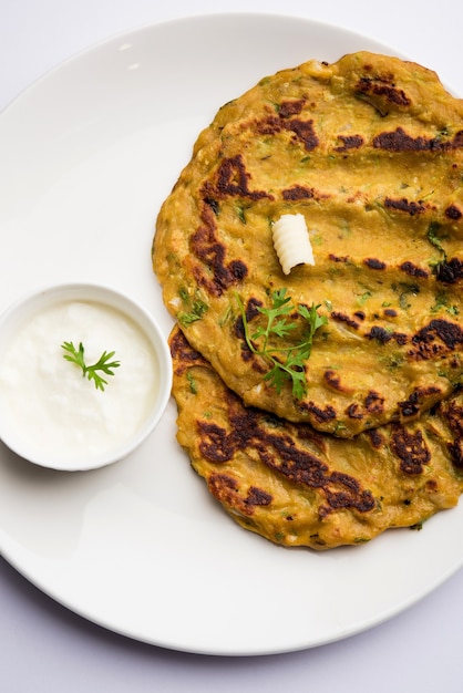 Thalipeeth é um tipo de panqueca saborosa com vários grãos, popular em Maharashtra, na Índia, servida com coalhada, manteiga ou ghee