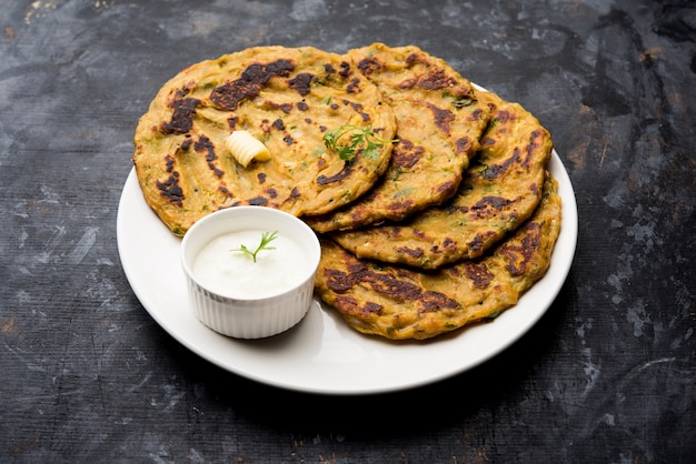 Thalipeeth é um tipo de panqueca saborosa com vários grãos, popular em Maharashtra, na Índia, servida com coalhada, manteiga ou ghee