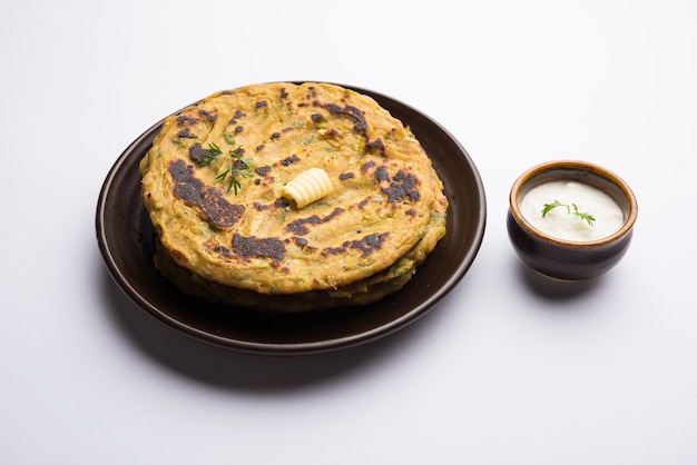 Thalipeeth é um tipo de panqueca saborosa com vários grãos, popular em Maharashtra, na Índia, servida com coalhada, manteiga ou ghee