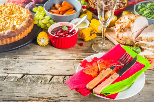 Thanksgiving-Familienessen Einstellung Konzept. Traditionelles Thanksgiving-Essen mit Truthahn, grünen Bohnen und Kartoffelpüree, Füllung, Kürbis-, Apfel- und Pekannusstorten, rustikaler Holztisch