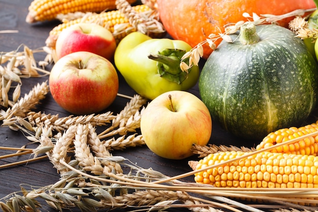 Thanksgiving - verschiedene Kürbisse mit Nüssen, Beeren und Getreide vor Holzbrett