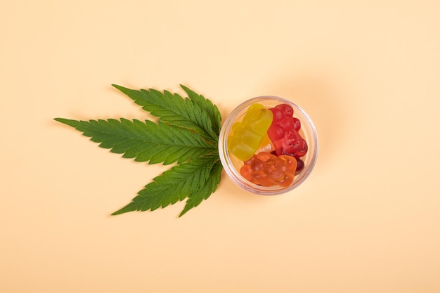 Thc-Geleebonbons, Cannabisbonbons, Drogen und grünes Blatt auf gelbem Hintergrund