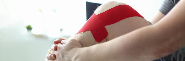 Therapeutische Behandlung des Beins mit rotem Physiotape