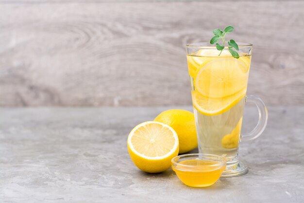 Therapeutisches Getränk aus Zitrone, Honig und Minze in einem Glas auf dem Tisch