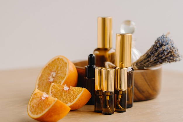 Ätherisches Öl in Flaschen mit dem Aroma von Orange und Lavendel, das auf einer Holzoberfläche liegt