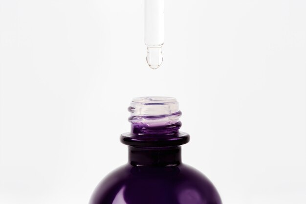 Ätherisches Öl oder Serum tropft von der Pipette in die Flasche