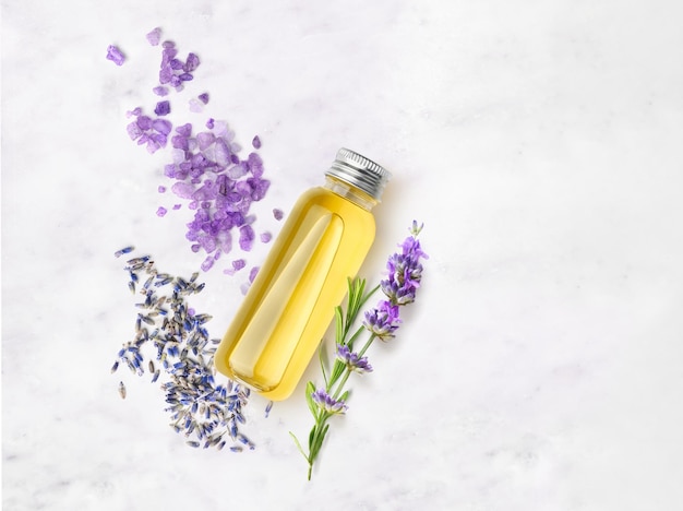 Ätherisches Öl und Lavendelsalz mit Blumen auf einem Marmortisch