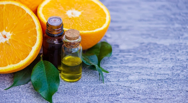 Ätherisches Orangenöl in einer Flasche, frische Fruchtstücke auf der Oberfläche